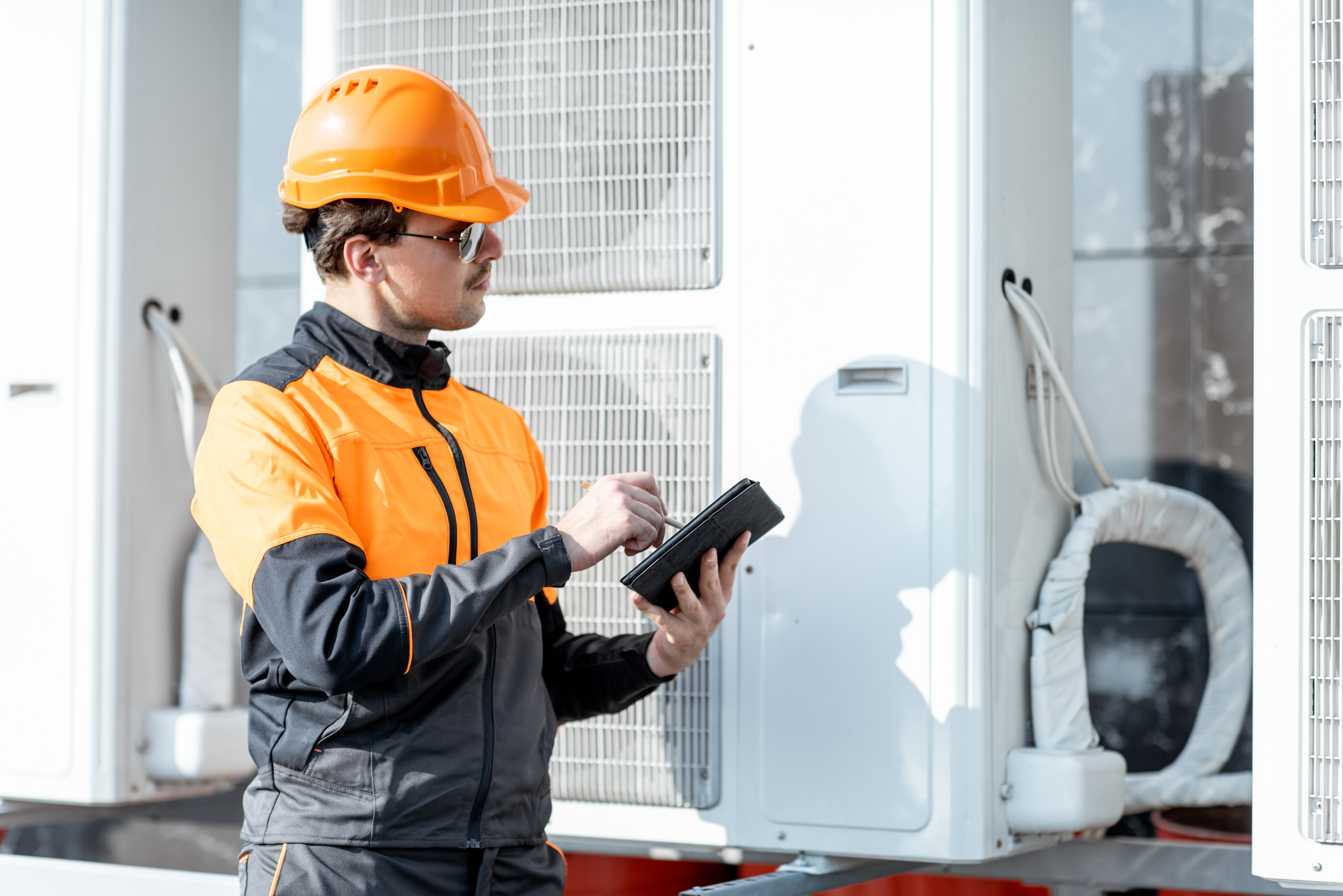 A worker is checking on the heat pump